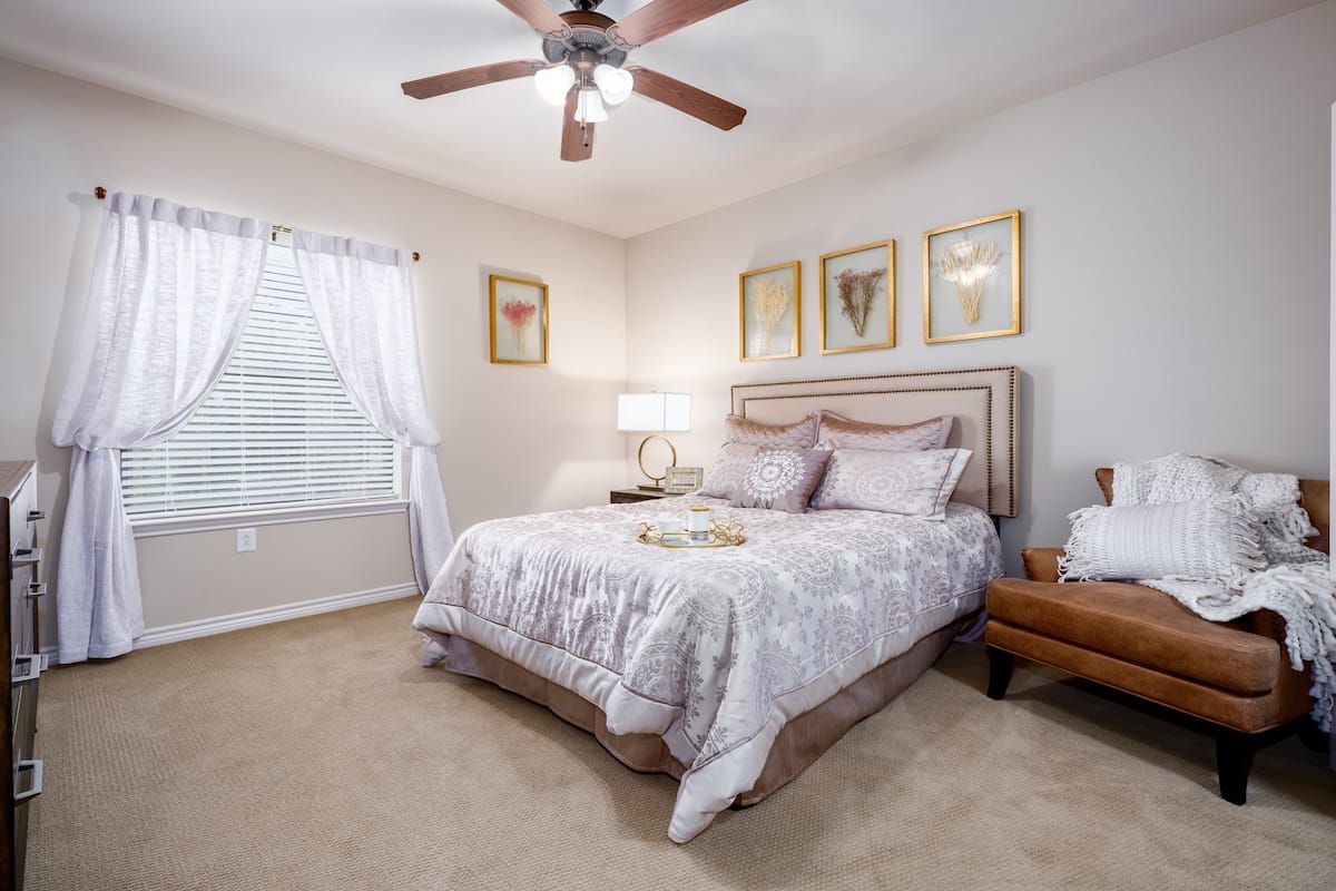 A cozy bedroom with a large bed, ceiling fan, and elegant decor.