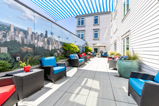 A stylish rooftop terrace with blue seating and vibrant planters, perfect for relaxing in an urban environment.