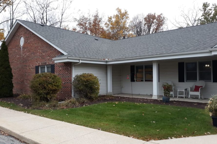 A suburban single-story brick house with a porch and a small front yard.