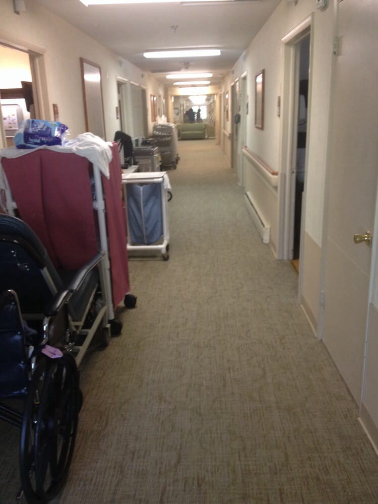 A hospital corridor with medical equipment and trolleys along the sides.