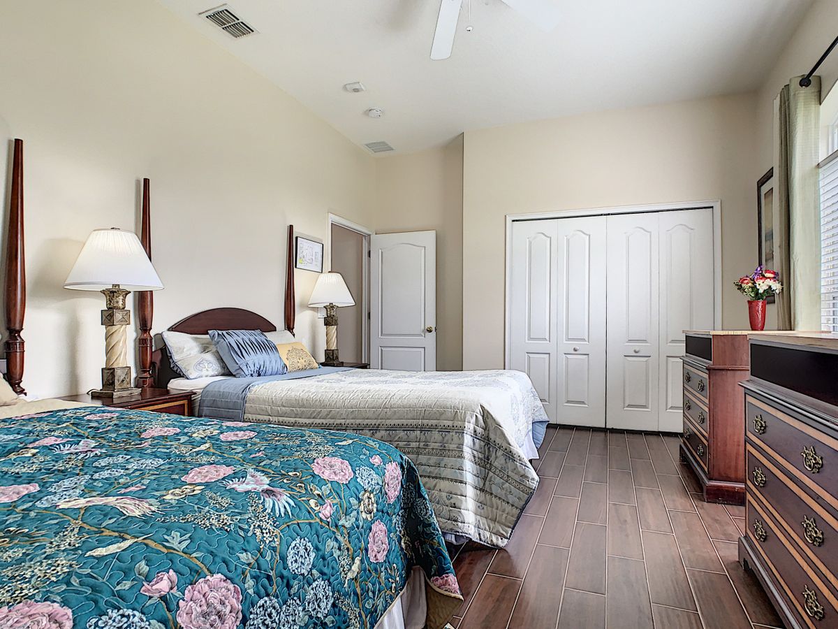 A cozy bedroom with two beds, matching lamps, and a wooden floor.