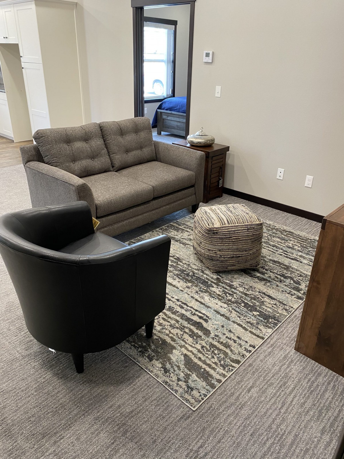 A cozy living room setup featuring a sofa, armchair, and a rug.