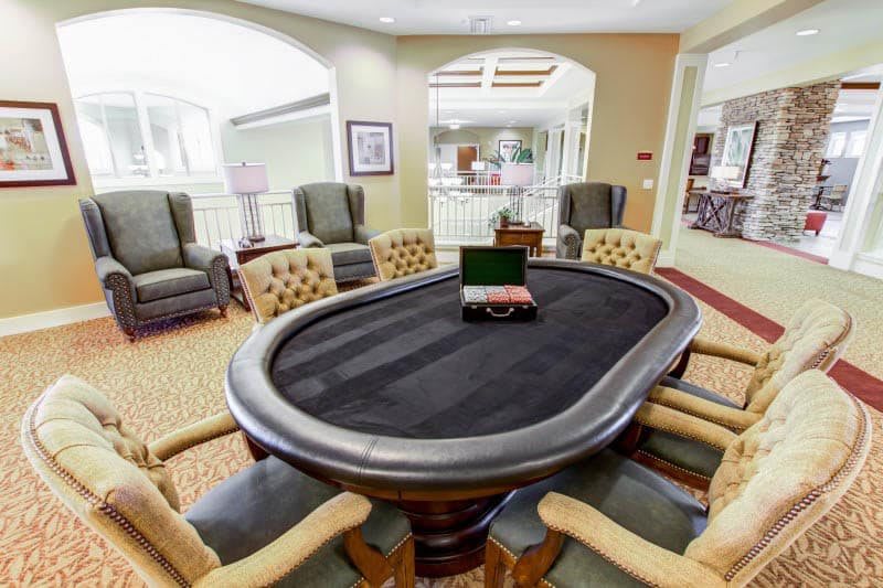 A well-furnished game room featuring a poker table and comfortable seating.
