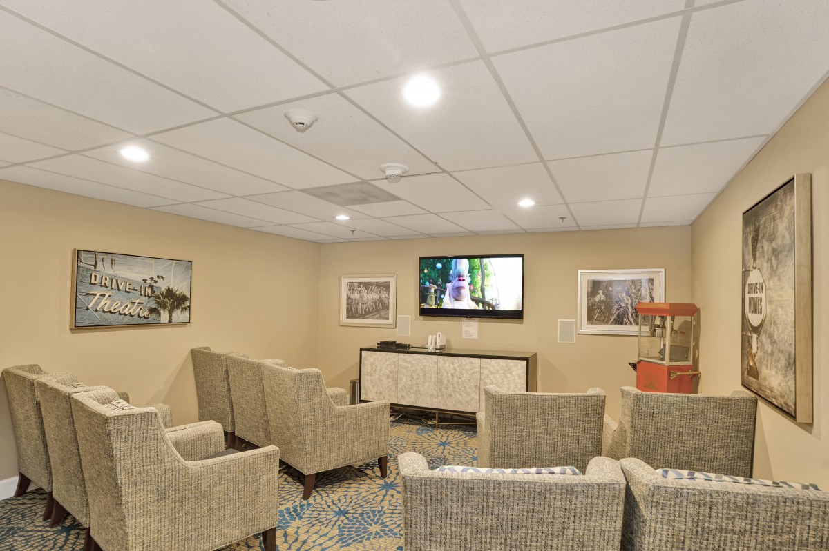 A cozy home theater room with comfortable seating and a large TV on the wall.