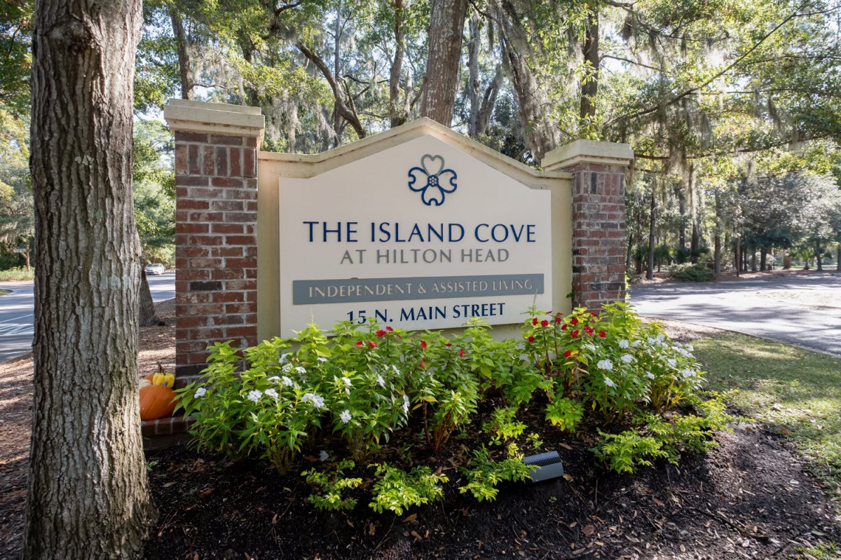 Entrance sign for The Island Cove at Hilton Head, surrounded by greenery and brick columns.