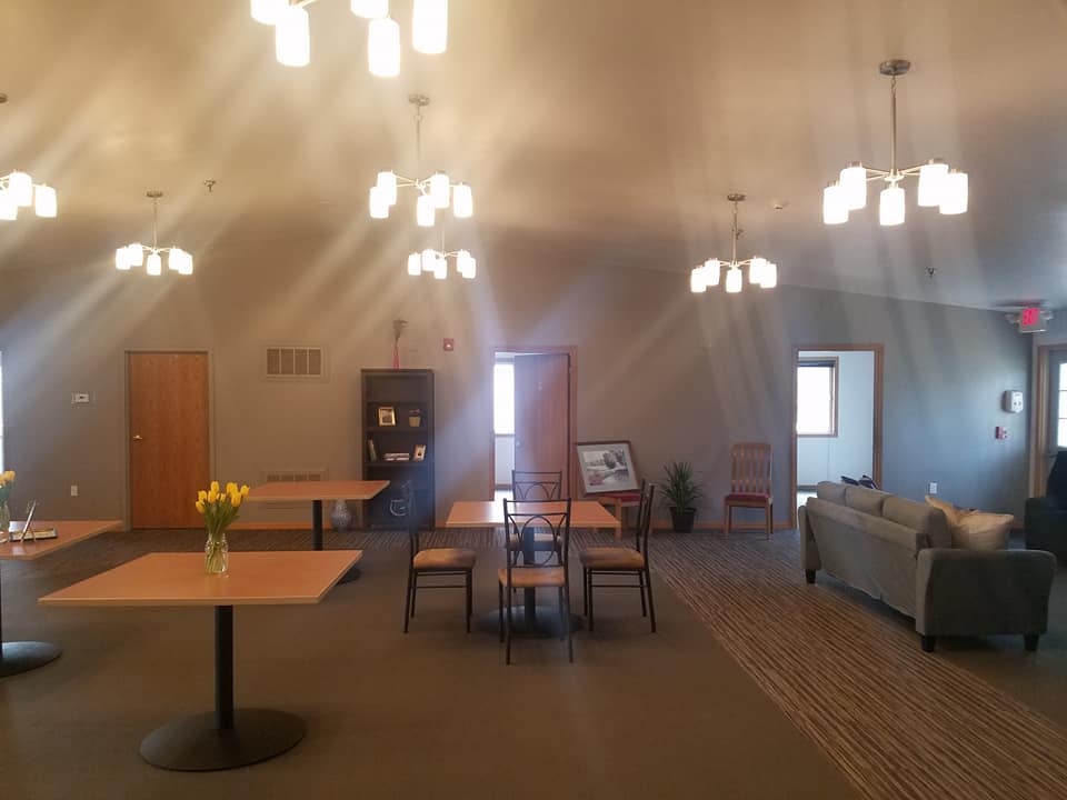 A warmly lit room with tables, chairs, and a sofa arranged for a cozy atmosphere.