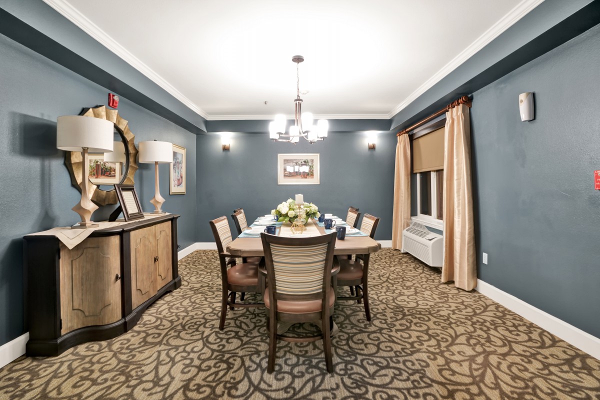 A beautifully decorated dining room featuring a central table with chairs, a chandelier, and elegant decor.