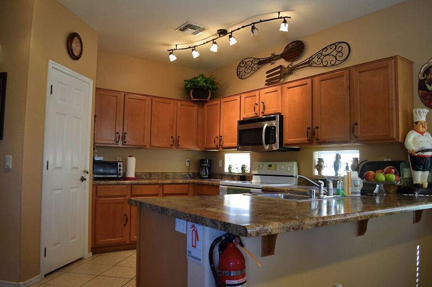 A cozy kitchen with wooden cabinets, modern appliances, and decorative lighting.