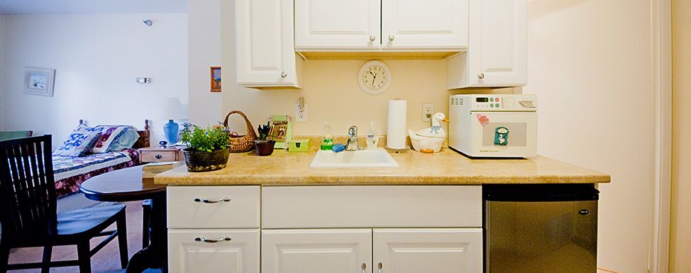 A tidy kitchen with white cabinets, a sink, and various appliances on the countertop.