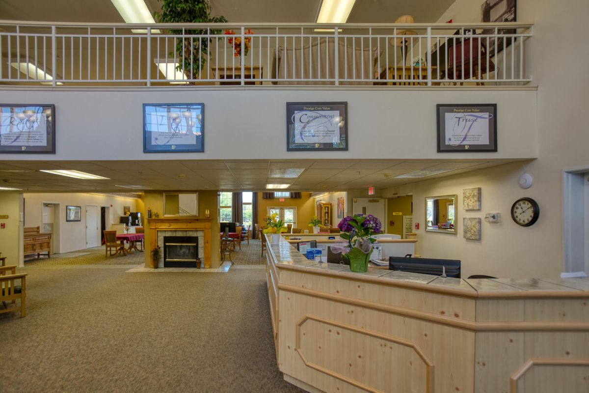 A reception area with a wooden desk, artwork on the walls, and comfortable seating.
