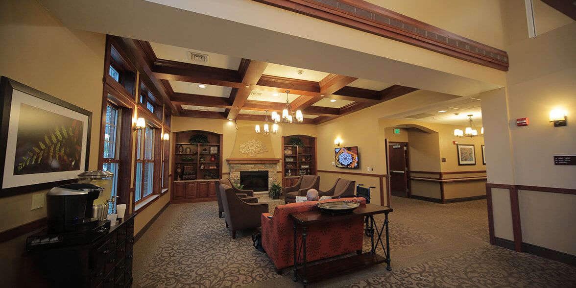 A cozy living room with a coffered ceiling, chandelier, and comfortable seating facing a television.