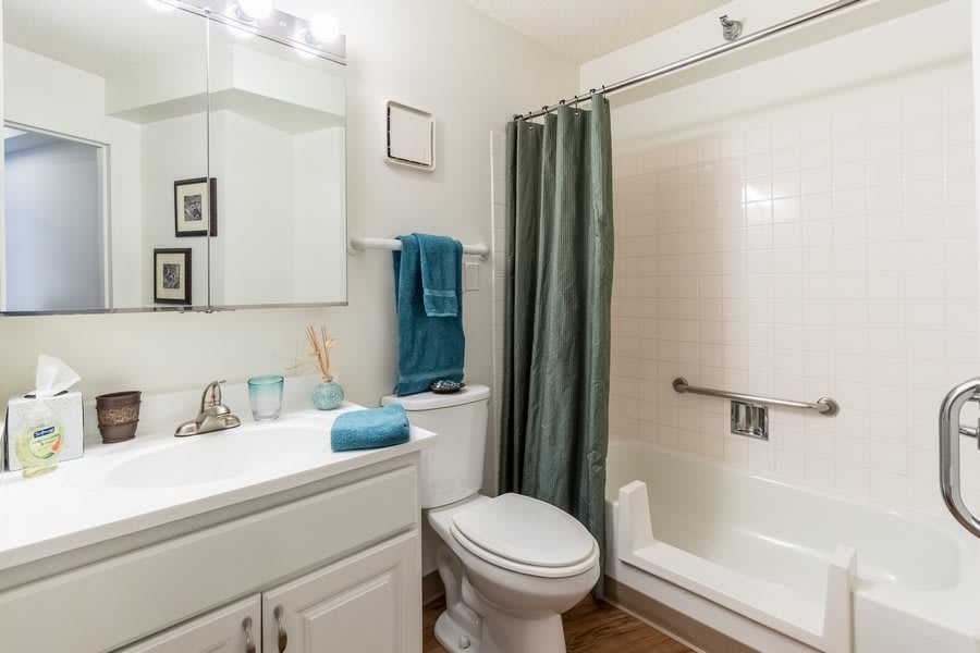 A clean and modern bathroom featuring a sink, toilet, and shower with a green curtain.