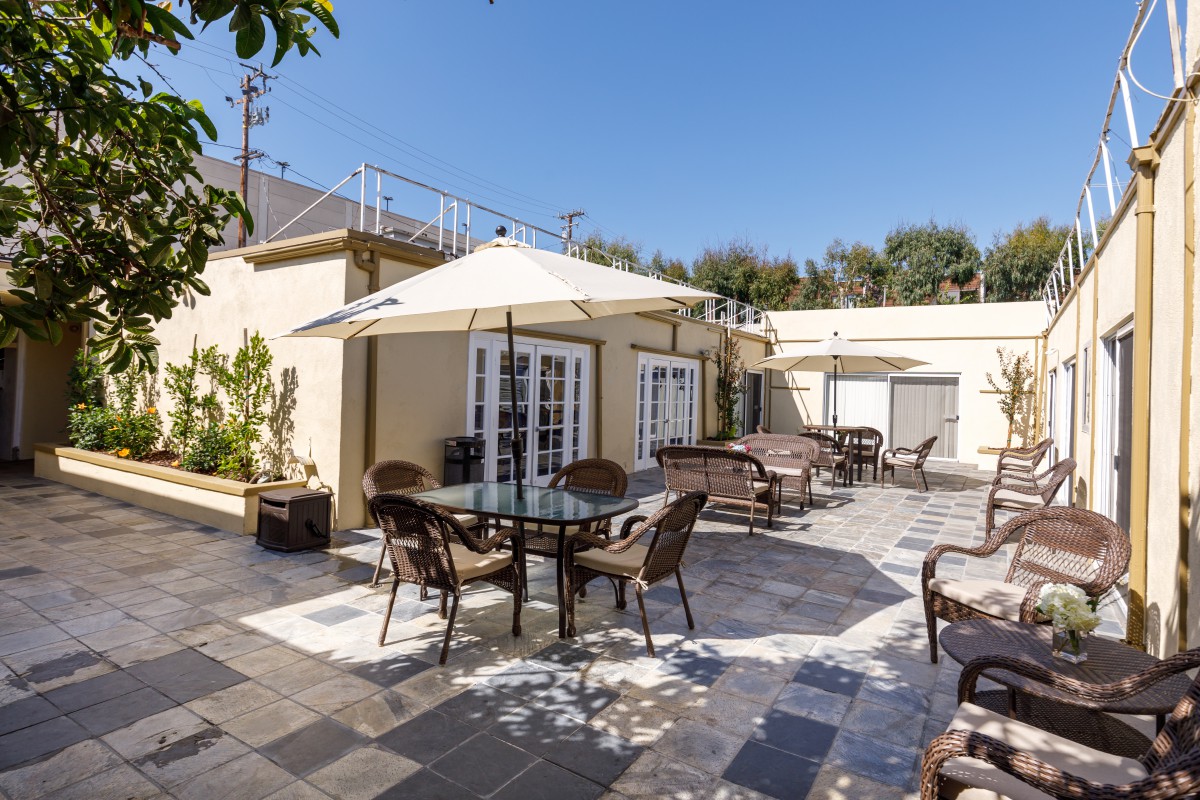 A sunny patio with tables, chairs, and umbrellas for outdoor seating.