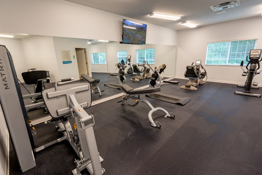 A modern gym equipped with various exercise machines and a wall-mounted TV.