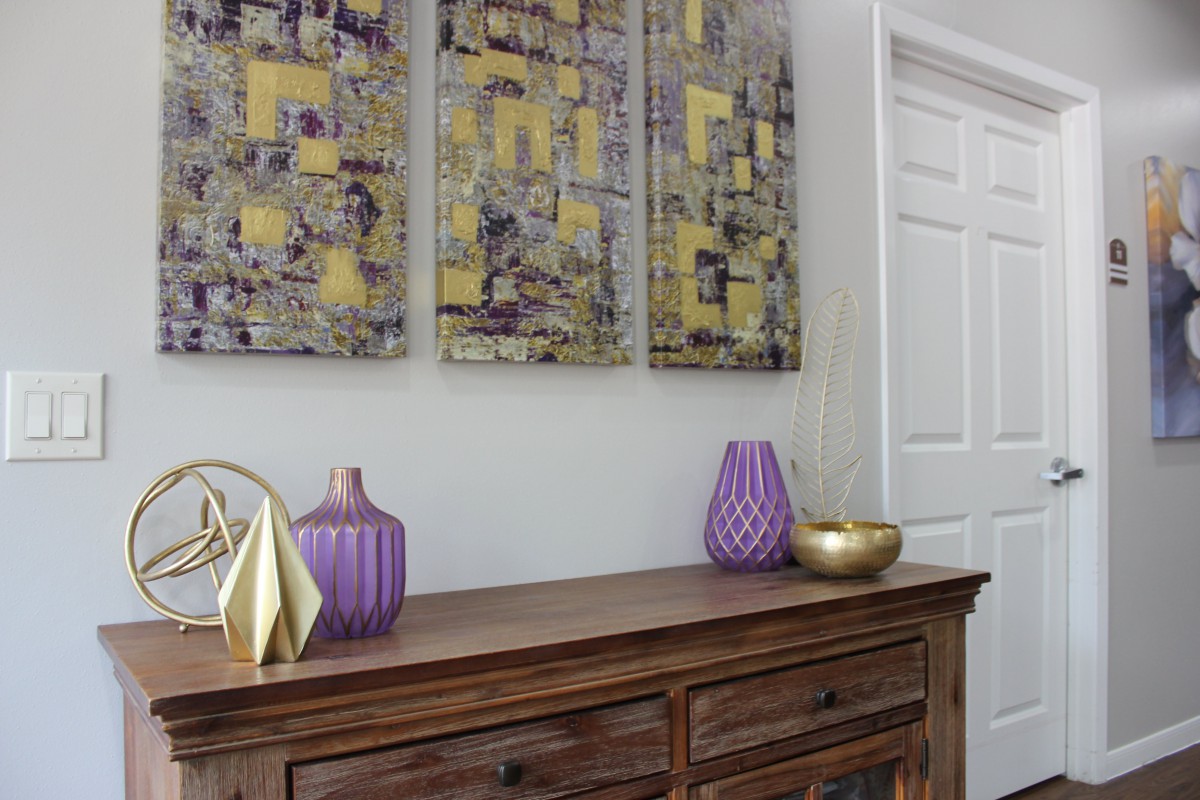 A stylish interior featuring a wooden sideboard adorned with decorative vases and modern artwork.