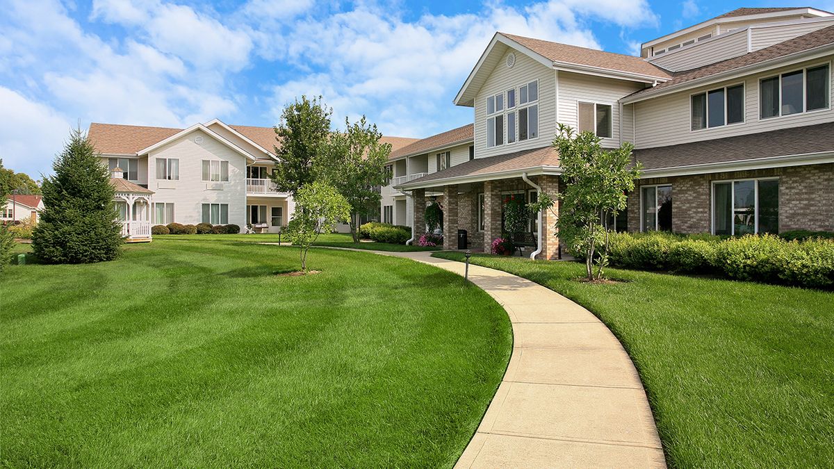 A well-maintained residential complex with lush green landscaping and a winding pathway.