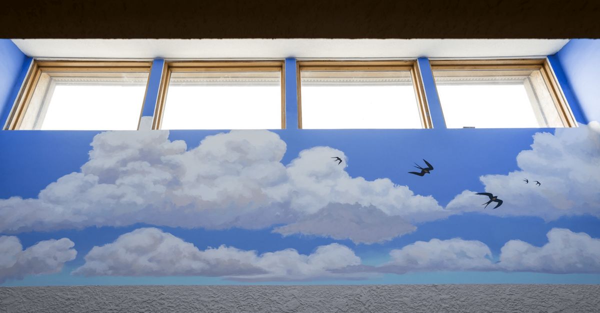 A mural depicting clouds and birds under a set of three windows.