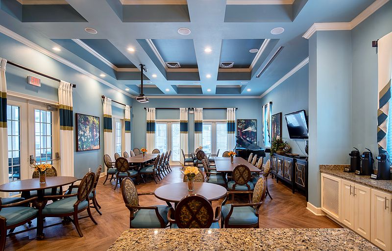 A modern dining area with elegant tables and chairs, featuring blue walls and ceiling lights.