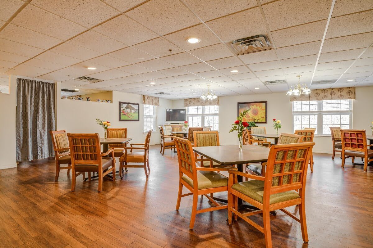 A well-lit dining area with wooden chairs and tables, featuring a cozy interior design.
