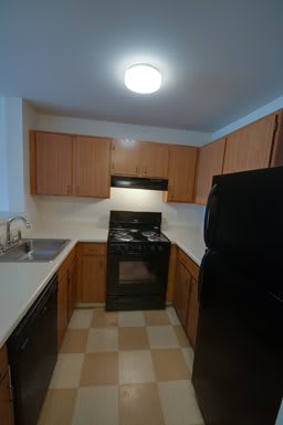 A kitchen with wooden cabinets, a black stove, and a sink.