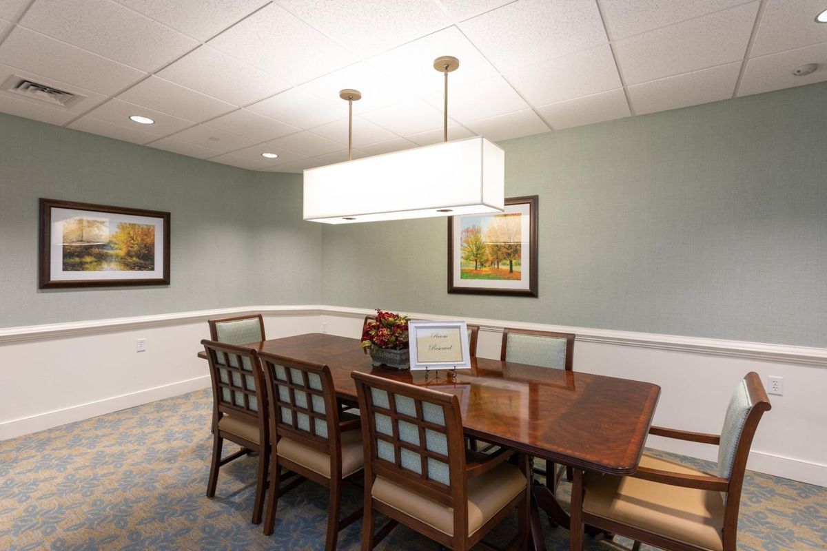 A well-organized conference room with a central table and chairs, featuring modern lighting and framed artwork on the walls.