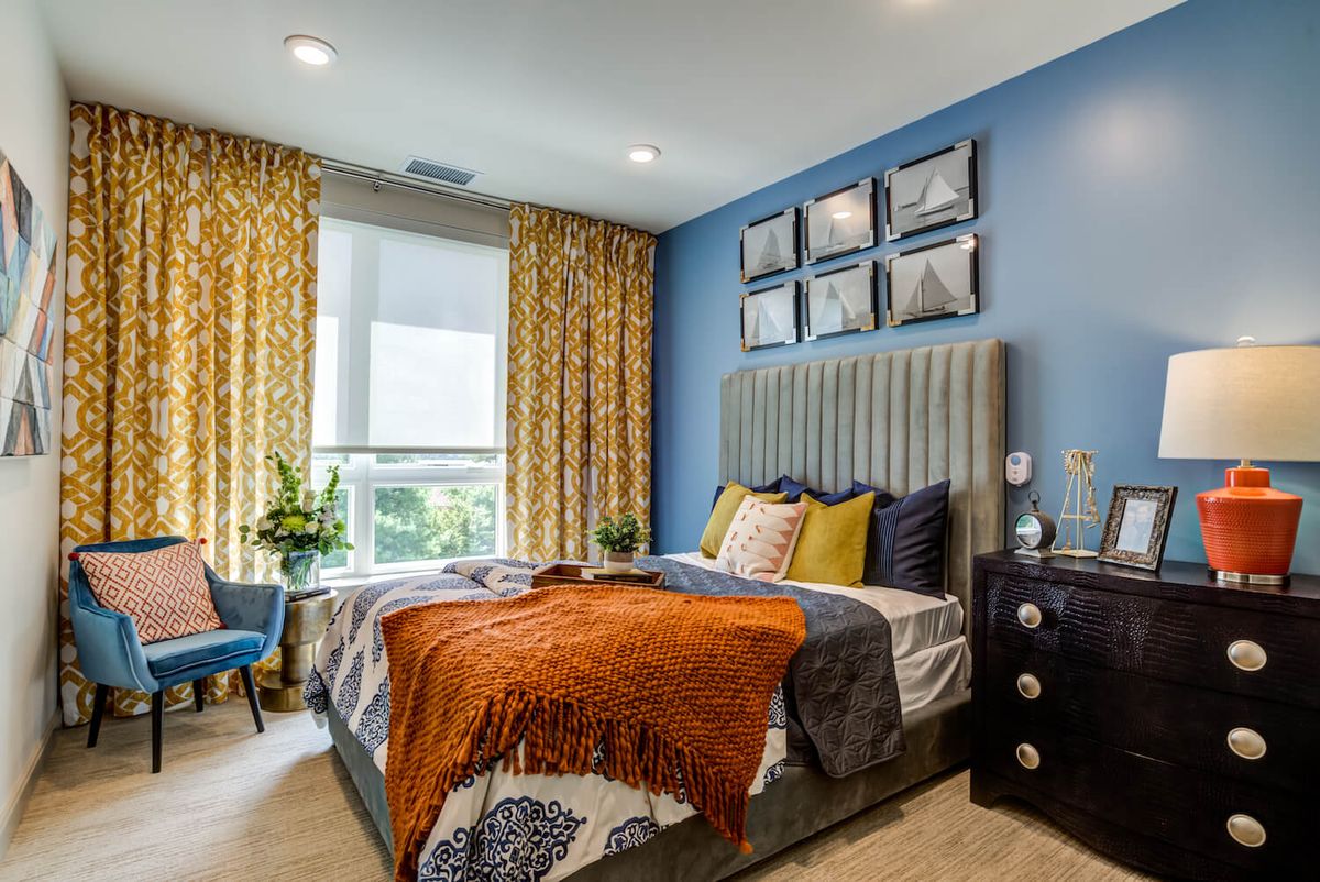 A beautifully designed bedroom with blue walls, vibrant curtains, and elegant decor.
