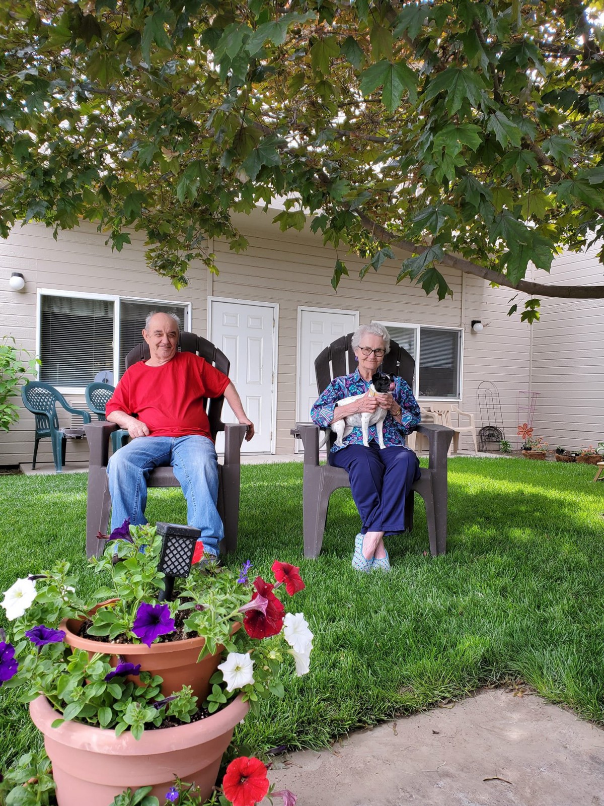 Two people sitting in chairs, relaxing in a garden surrounded by flowers.