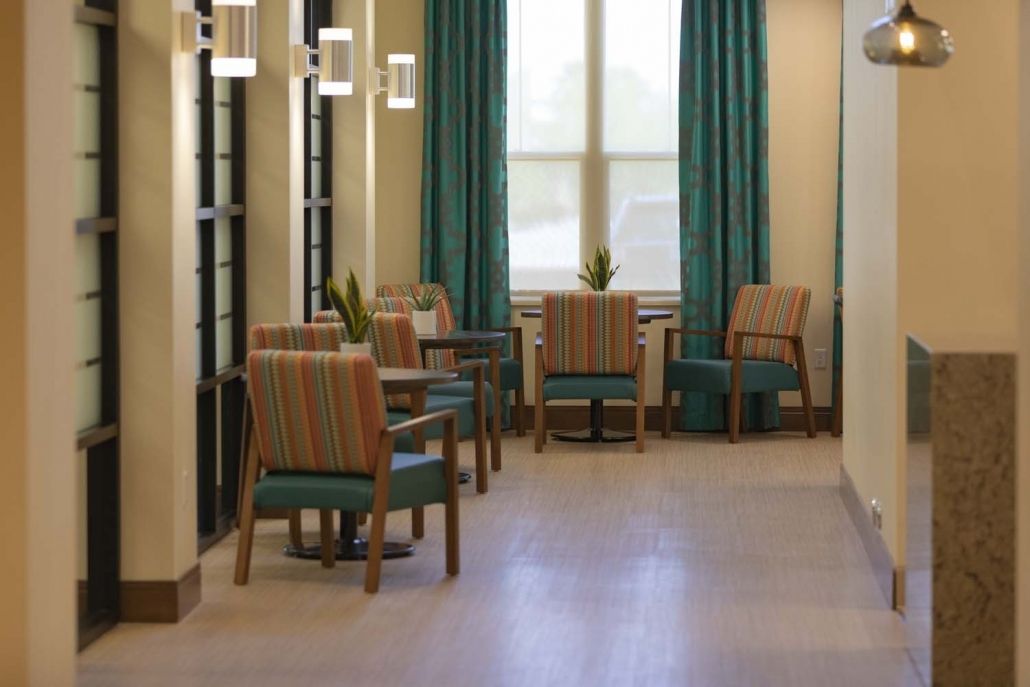 A modern lobby seating area with chairs and tables arranged by large windows.