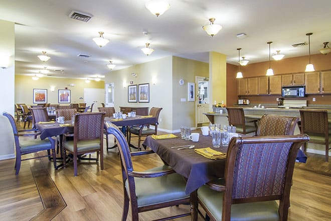 A well-lit dining area with neatly arranged tables and chairs, featuring a warm ambiance and wooden flooring.