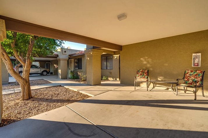 A spacious covered patio with a bench in a residential outdoor setting.