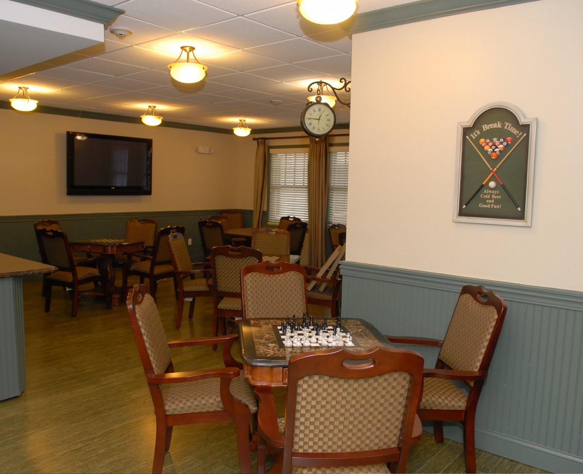 A cozy game room featuring a chess board, dartboard, seating area, and a television.