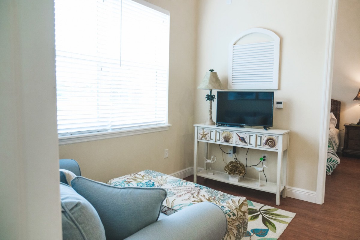 A cozy living room corner with a sofa and TV stand next to a window providing ample natural light.