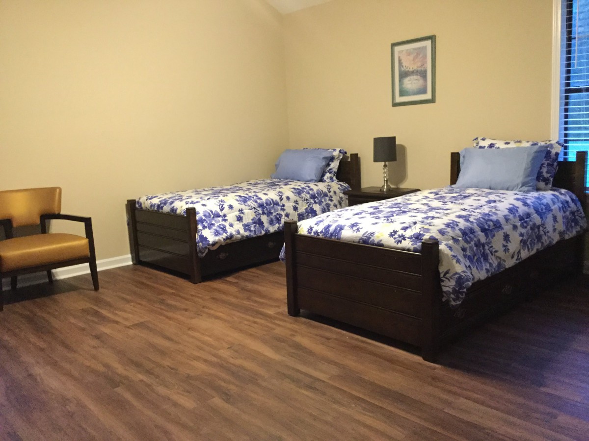 A bedroom with two single beds featuring floral bedding and wooden floors.
