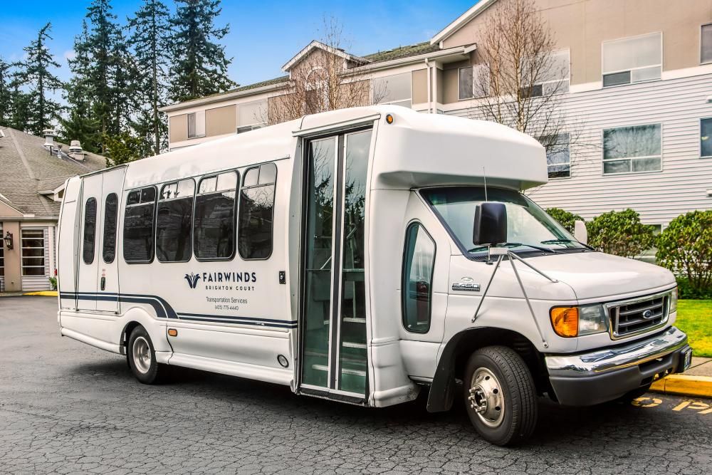 A white shuttle bus parked on a street in front of a building.