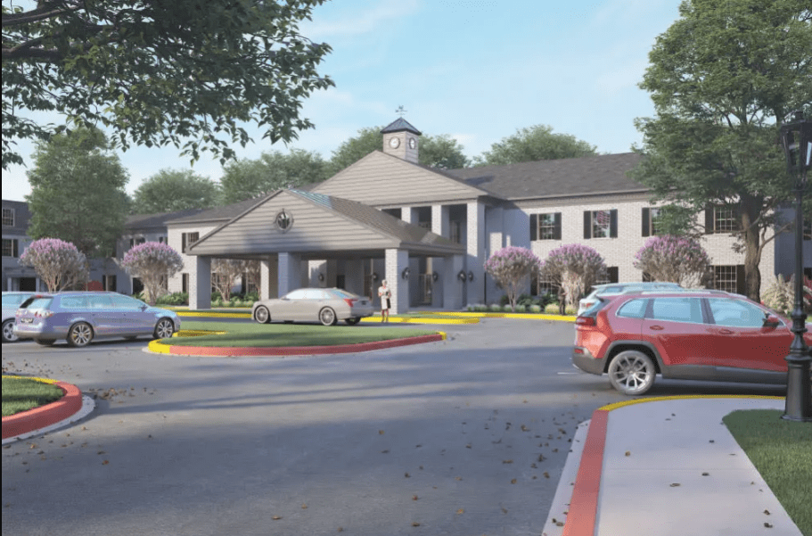 A driveway entrance to a building with cars parked nearby.