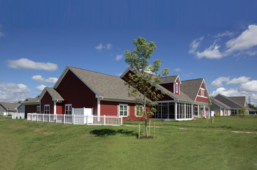 A charming red house with a green lawn under a clear blue sky.