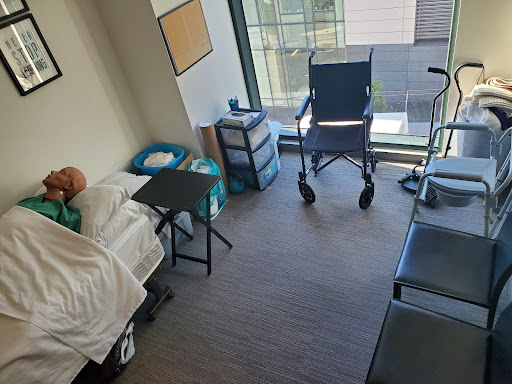 A view of a hospital room equipped with a bed, a wheelchair, and other medical furnishings.