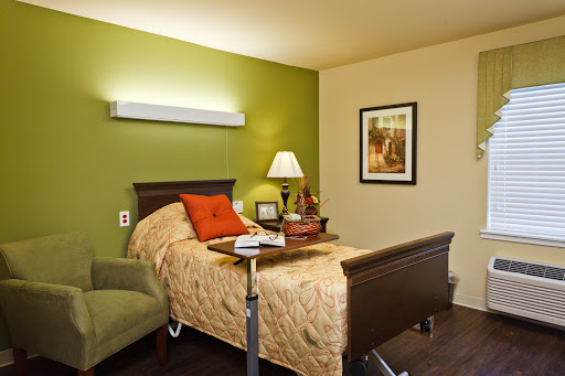 A cozy bedroom featuring a bed with decorative pillows, a bedside lamp, and a comfortable chair.