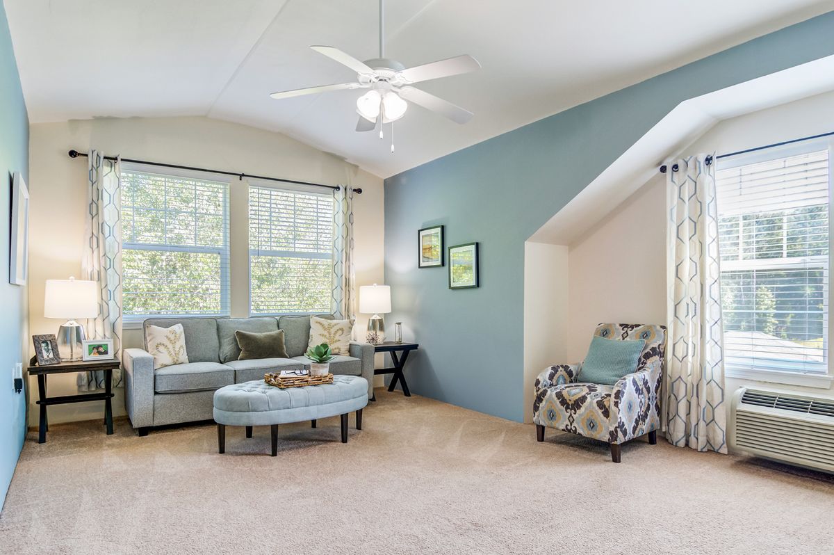 A cozy living room featuring a sofa, armchair, and coffee table against a blue accent wall.