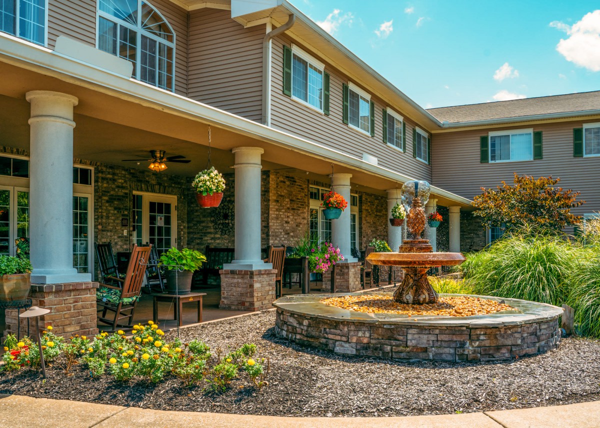 A beautiful patio area with a central fountain surrounded by lush landscaping and comfortable outdoor seating.