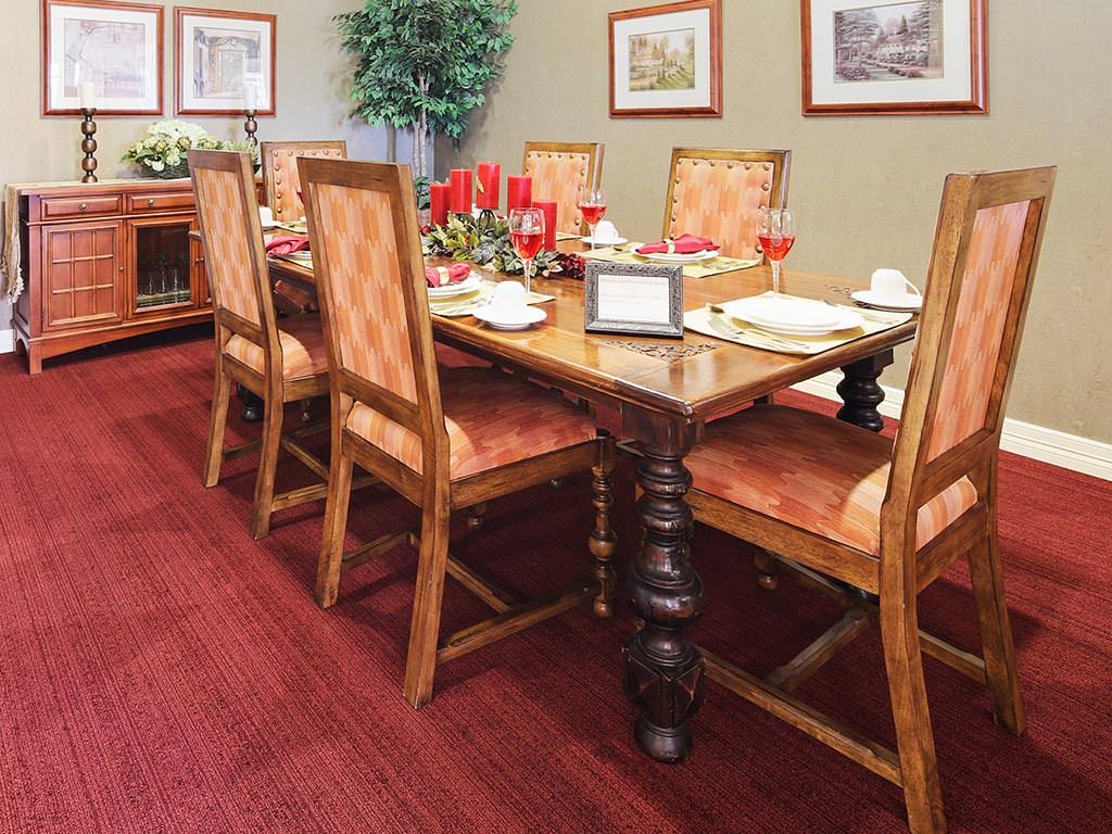 A dining room with a wooden table set for a meal, featuring upholstered chairs and decorative accents.