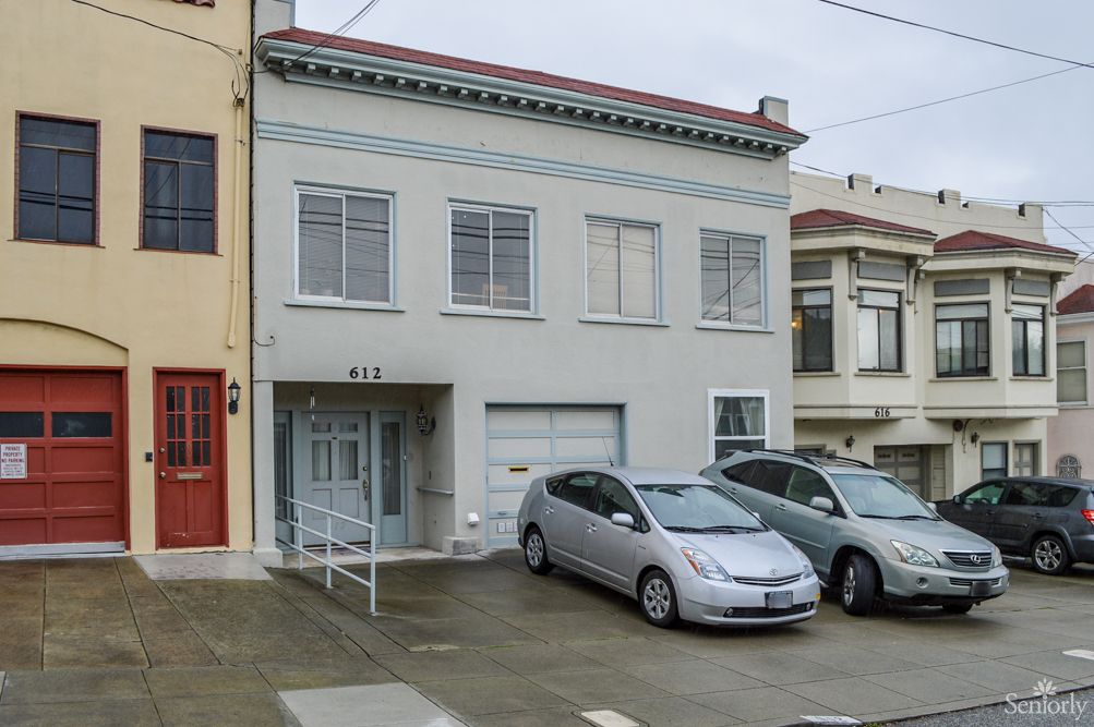 A residential house with parked cars in an urban neighborhood.