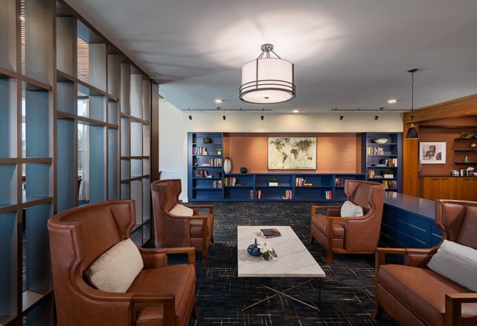 Modern lounge area with comfortable armchairs, a central coffee table, and built-in bookshelves.