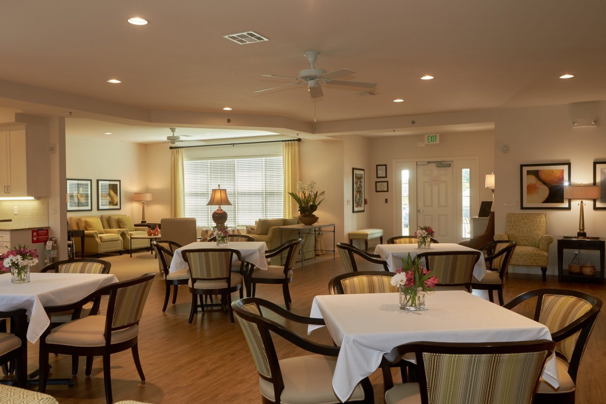 A cozy dining room with elegantly arranged tables and chairs, featuring warm lighting and inviting decor.
