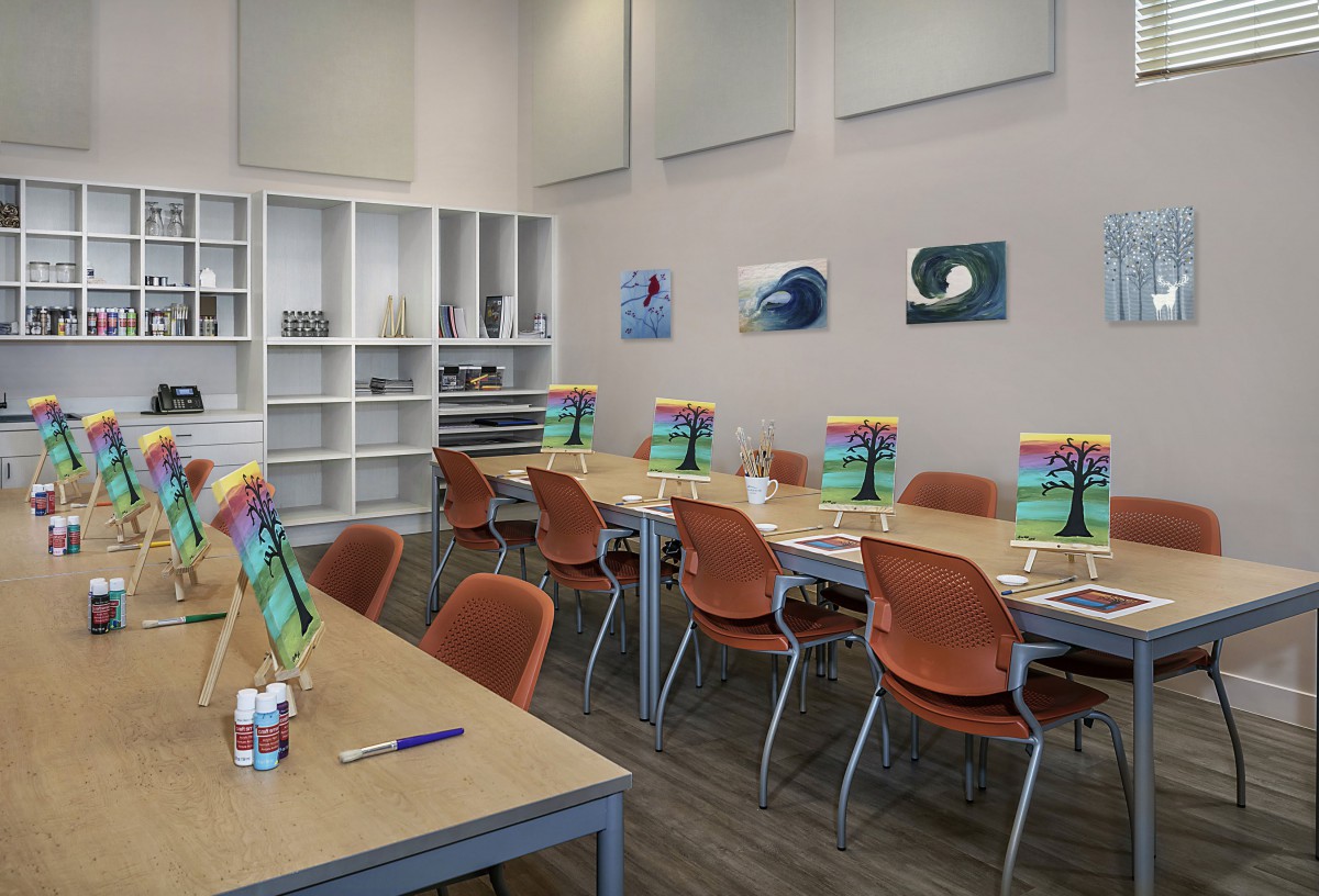 A well-lit classroom set up for art activities with tables and chairs arranged neatly, complete with art supplies and paintings on the walls.