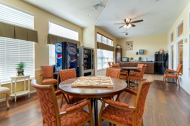 A bright community room with tables, chairs, and vending machines.