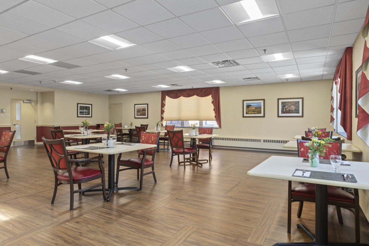 A well-lit dining area with neatly arranged tables and chairs, featuring framed artwork on the walls.