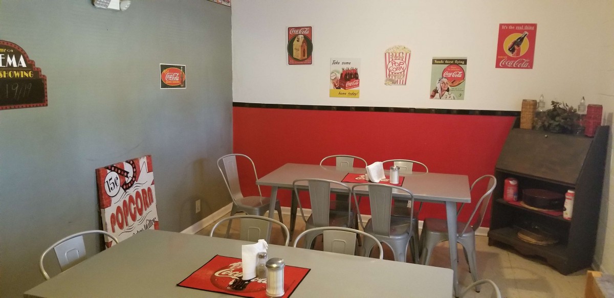 A cozy diner with red and gray decor, featuring vintage wall art and metal seating.