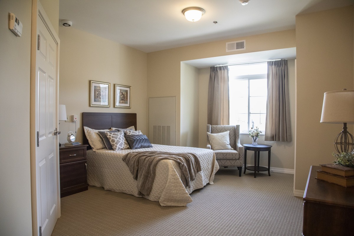 A cozy bedroom interior with a neatly made bed, bedside tables, and a window with curtains.