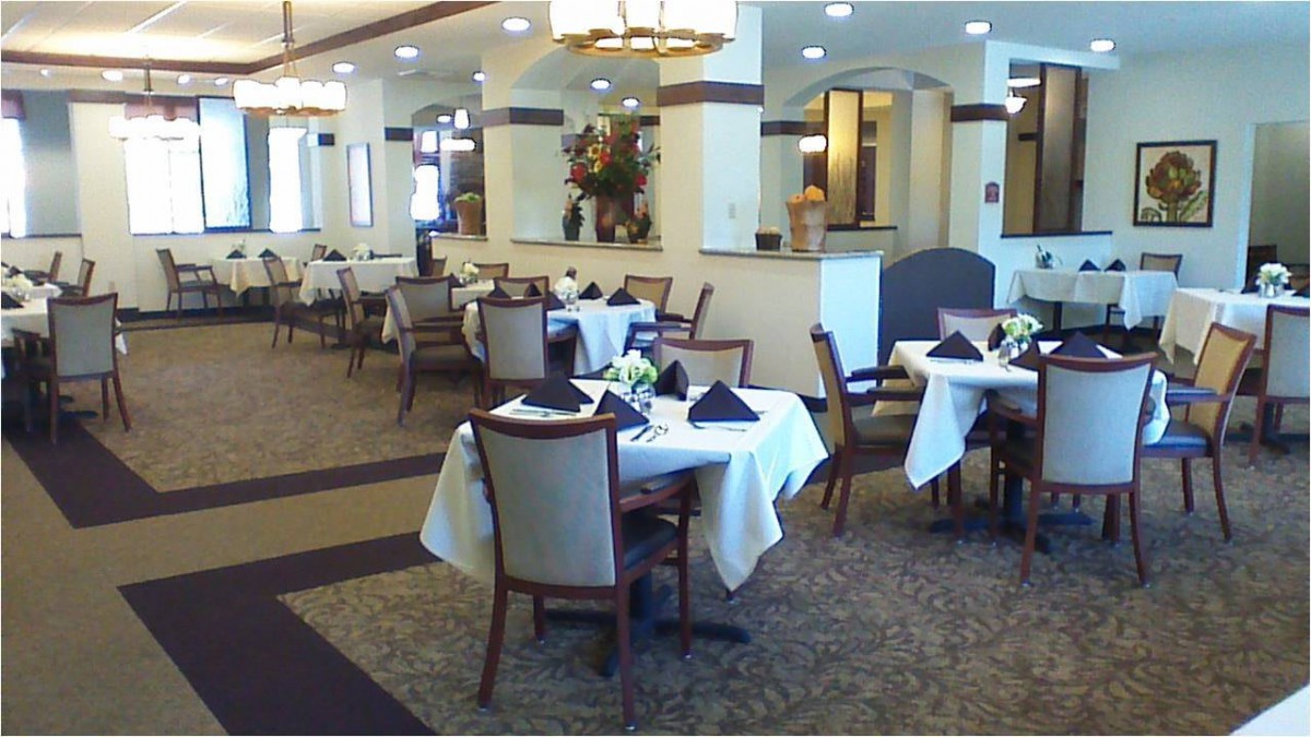 An elegant restaurant dining area with neatly arranged tables and chairs, featuring formal table settings.